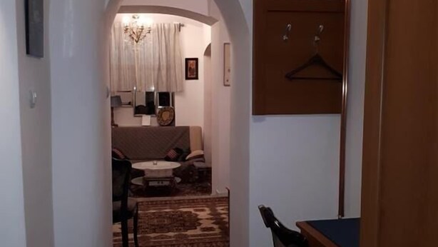 A narrow hallway with a patterned rug, a dining area with a table and chairs, and a seating area with a sofa and a small table. - Apartment Milan (Zagreb)