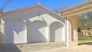 Un edificio con tres puertas de garaje, fachada de piedra y cielo despejado.