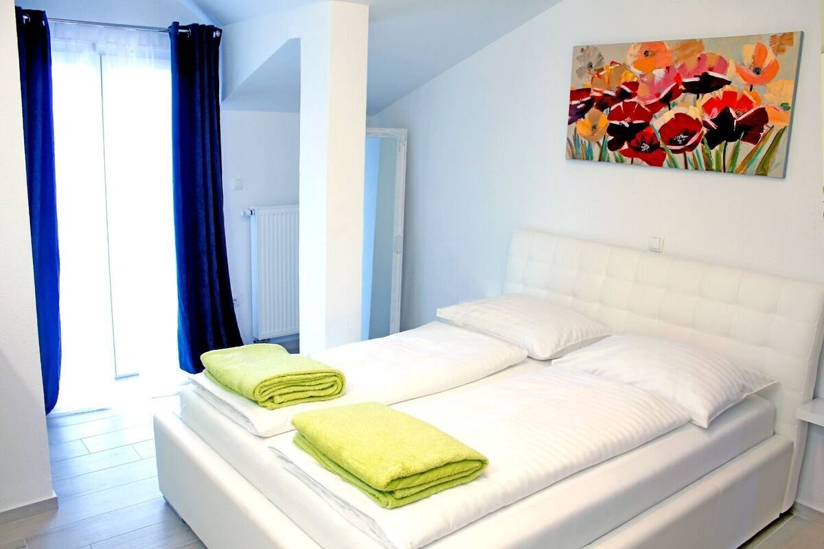 Una camera da letto con un letto, due cuscini e due asciugamani verdi.