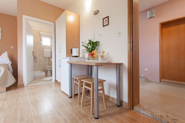 A compact room with a kitchenette, a small dining table, and a shower area. - Apartments Old Stone (Sukosan)