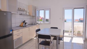 Une cuisine moderne avec un coin repas, un réfrigérateur, une machine à café et une fenêtre donnant sur un paysage pittoresque.