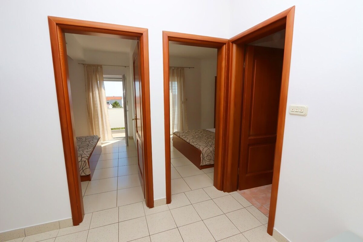 Ein Zimmer mit zwei Betten, einem Badezimmer und einem Gang, der zu einem Außenbereich führt.