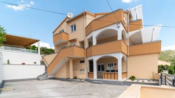 Un edificio de varios pisos con techo plano, un balcón y una escalera que conduce al nivel superior.