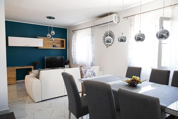 A modern living room with a sofa, TV, and dining table set. - House Franny (Zadar)