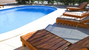 A swimming pool with wooden lounge chairs and a tiled deck. - House Franny (Zadar)