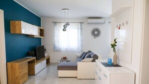 A modern living room with a TV, sofa, and a dining area with a table and chairs. - House Franny (Zadar)