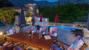 A wooden table with chairs and a pool in the background. - House Tonci (Tucepi)