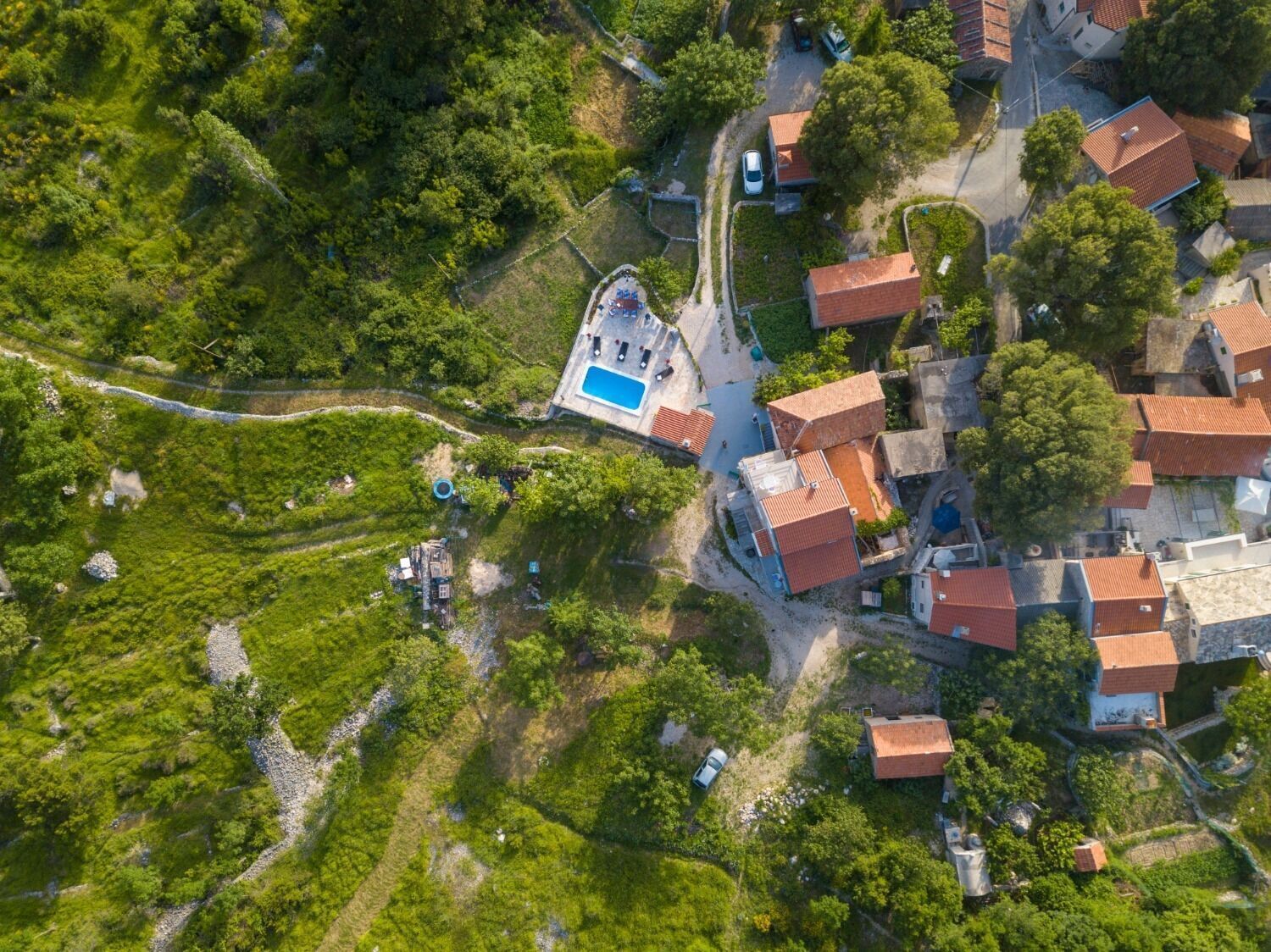 An aerial view of a residential area with houses, a swimming pool, and a winding path.
