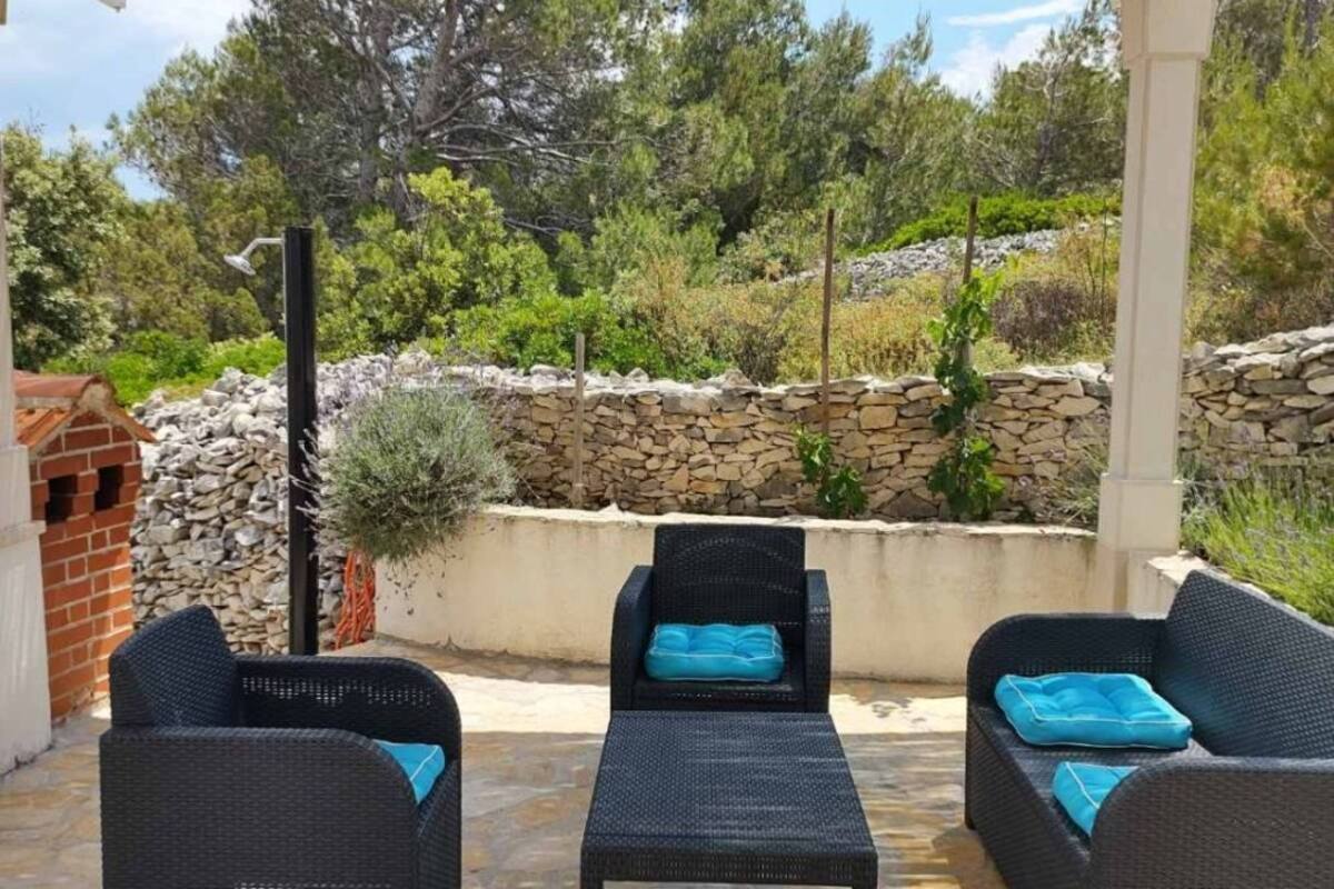 A covered outdoor seating area with wicker furniture and stone flooring.