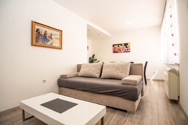 A modern living room with a sofa, a coffee table, and a painting on the wall. - Apartments Andelko (Baska Voda)