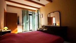 A hotel room with a large bed, a desk with a mirror, and a window with curtains. - Apartment Nives (Umag)