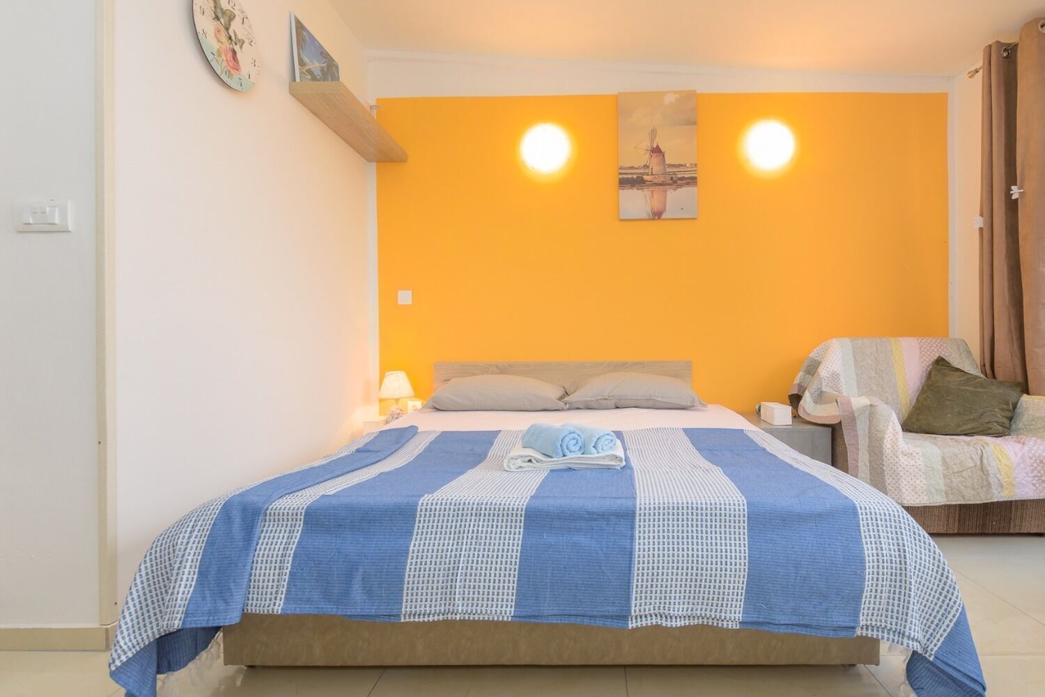 Ein Schlafzimmer mit einem Bett, einem Sessel und einer Wanduhr.