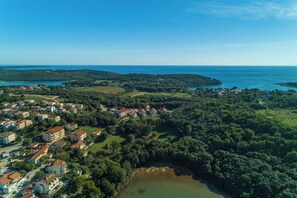 An aerial view of a coastal town with residential buildings, a lake, and a lighthouse in the distance. - Apartment Orange (Medulin)