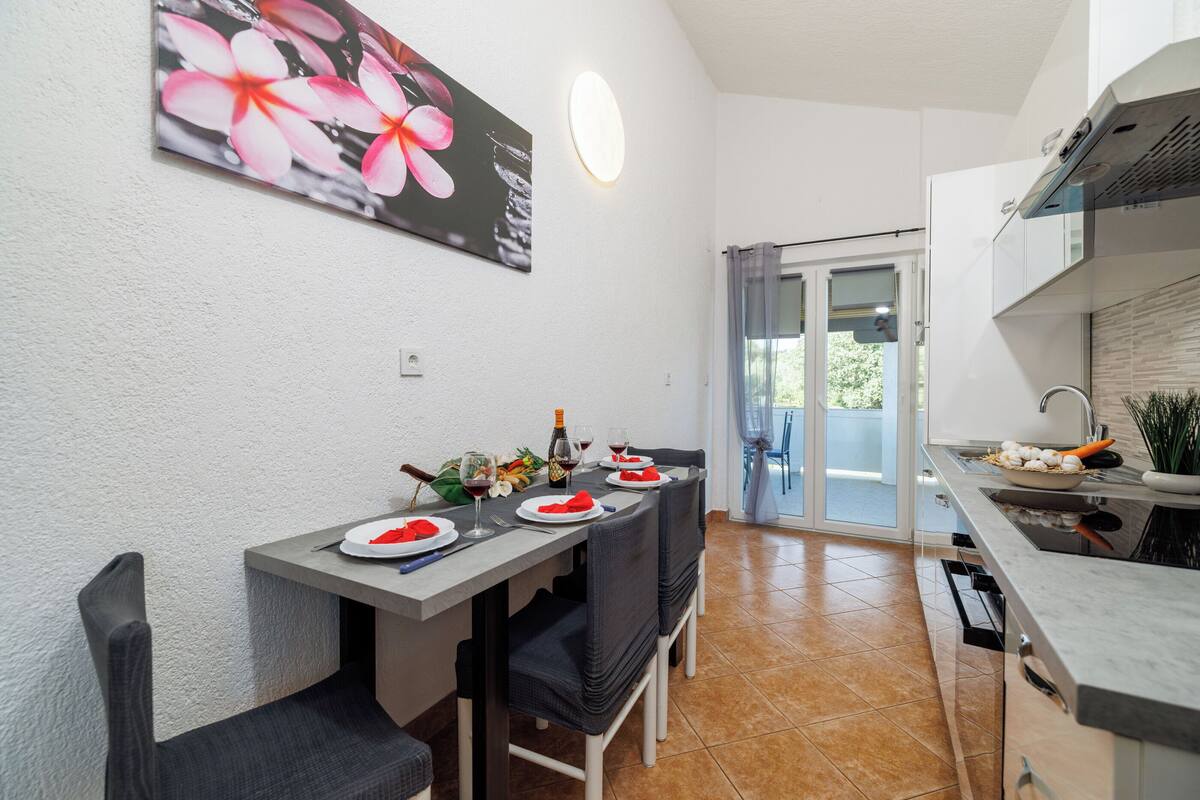 Une cuisine moderne avec un coin repas, comprenant une table mise pour deux personnes, avec assiettes, verres et une bouteille.