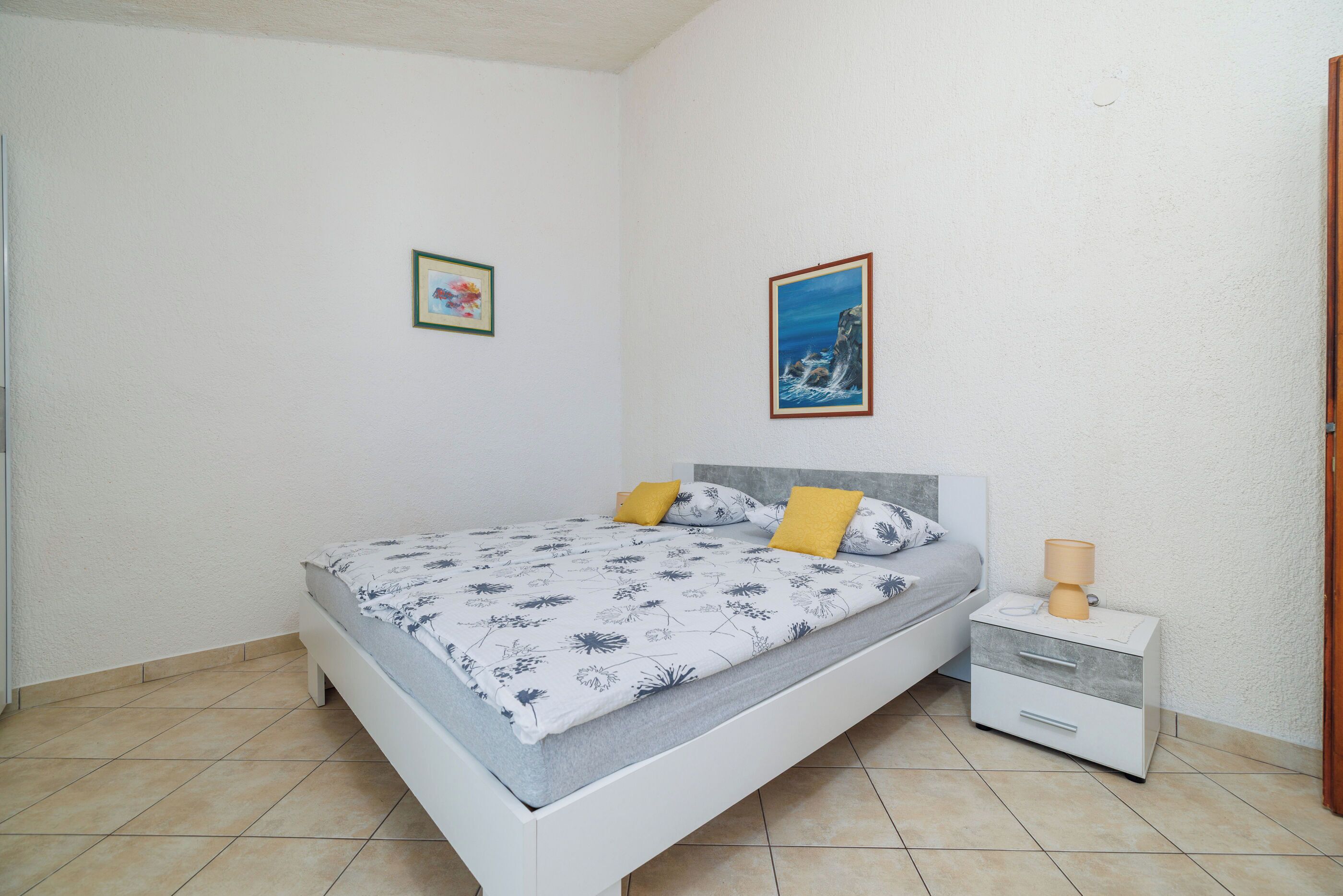 Une chambre à coucher avec un lit, une table de chevet et deux tableaux encadrés accrochés au mur.