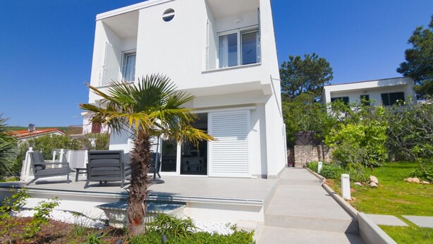A modern two-story house with a balcony, a palm tree, and a small garden area. - House Nika (Punat)