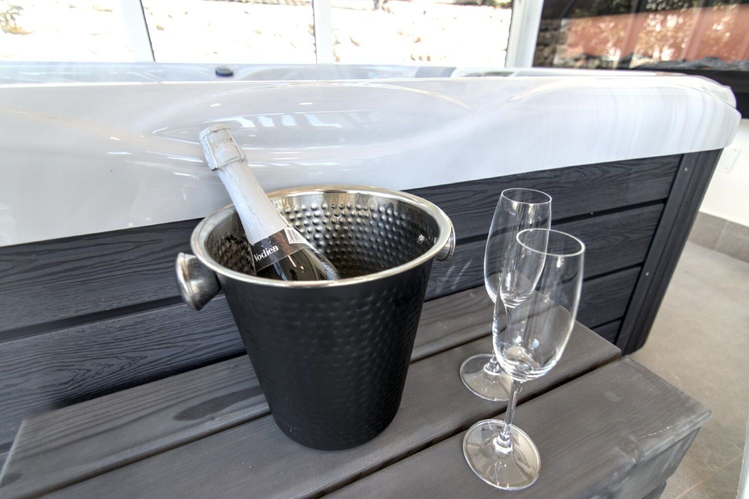 A black bucket with a bottle of vodka and a wine glass on a wooden table.