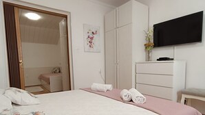 Une chambre à coucher avec un grand lit, un téléviseur fixé au mur et une armoire.