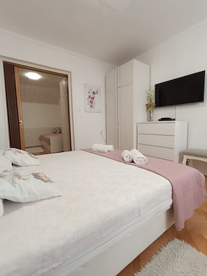 Ein Schlafzimmer mit einem großen Bett, einem an der Wand befestigten Fernseher und einem Kleiderschrank.