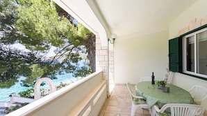 Un balcon avec une table et des chaises, donnant sur une étendue d’eau et des arbres.