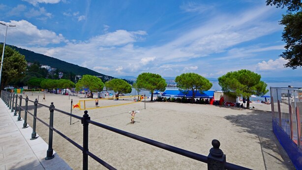 A beach volleyball court with a net, trees, and a clear sky. - Apartment Miriam (Opatija)