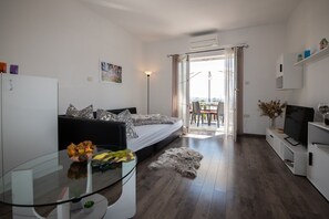 Ein modernes Wohnzimmer mit einer Couch, einem Glastisch, einem Fernseher und einem Balkon mit Blick.