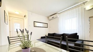 Ein modernes Wohnzimmer mit einem Glastisch, einer Couch und einer Zimmerpflanze.