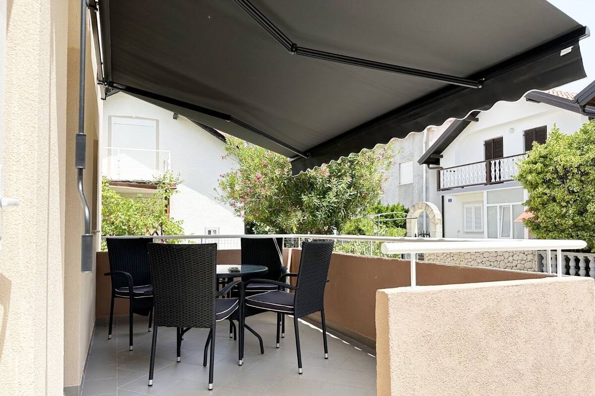 An outdoor patio with a covered seating area, a white table, and a stone wall.