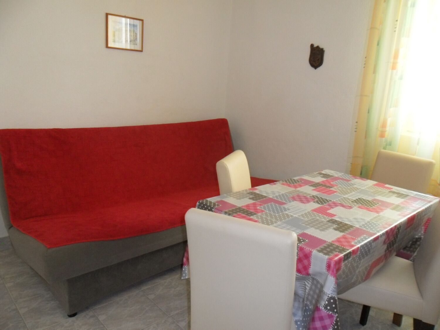 Ein Zimmer mit einem roten Sofa, einem Tisch mit einer Steude und einem Sessel.