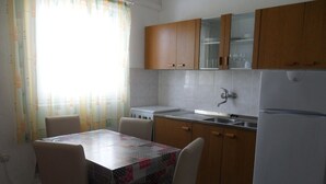 Una cocina con una mesa de comedor, sillas, estufa, pileta y refrigerador.