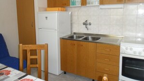 Una cocina compacta con armarios de madera, un refrigerador blanco, un lavamanos y un horno.