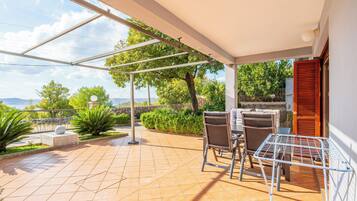 Un patio cubierto con suelo de baldosas, mobiliario exterior y vistas al paisaje.
