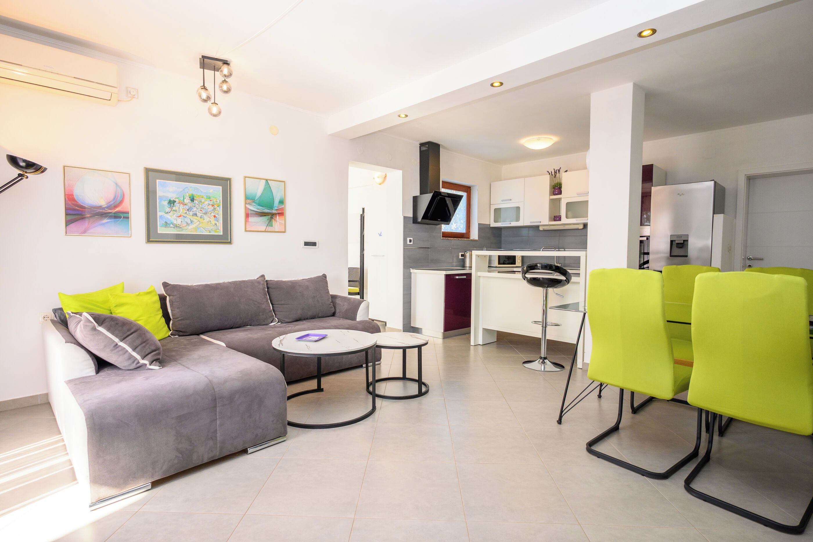 A modern living room with a grey sofa, two small tables, and a bright green chair.