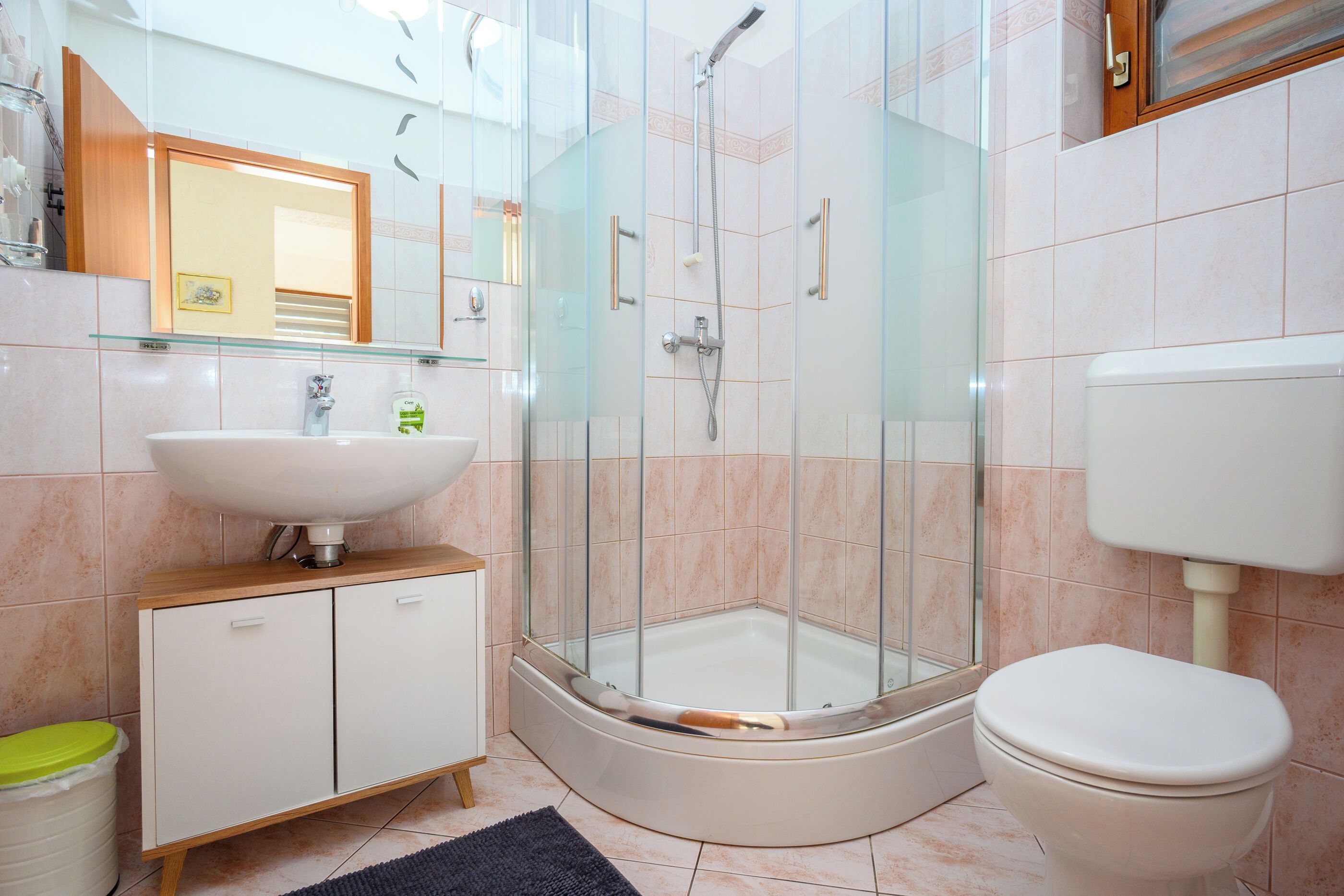 Un baño moderno con ducha envuelta en vidrio, un lavabo blanco y un inodoro.