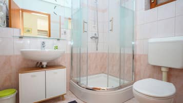 Un baño moderno con ducha envuelta en vidrio, un lavabo blanco y un inodoro.