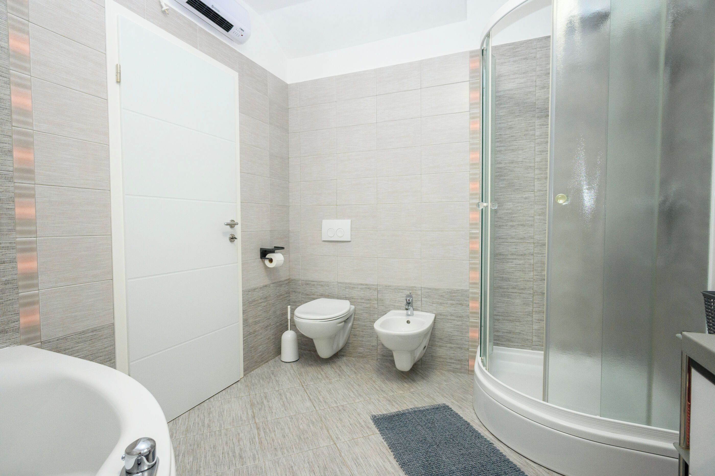 Ein modernes Badezimmer mit Duschkabine, Toilette, Bidet und Badewanne.