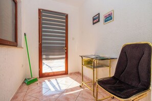 A room with a door, a chair, a small table, and a broom. - Apartments Ivni (Karlobag)