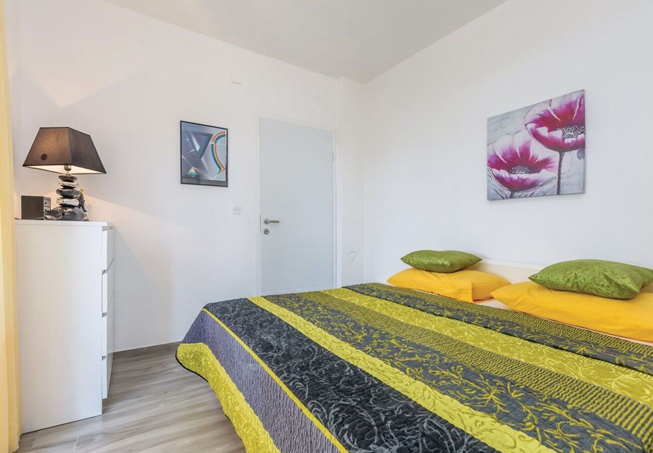Un dormitorio con una cama, una mesita de noche, una lámpara y dos cuadros en la pared.