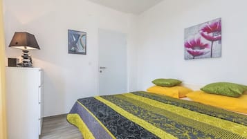 Un dormitorio con una cama, una mesita de noche, una lámpara y dos cuadros en la pared.