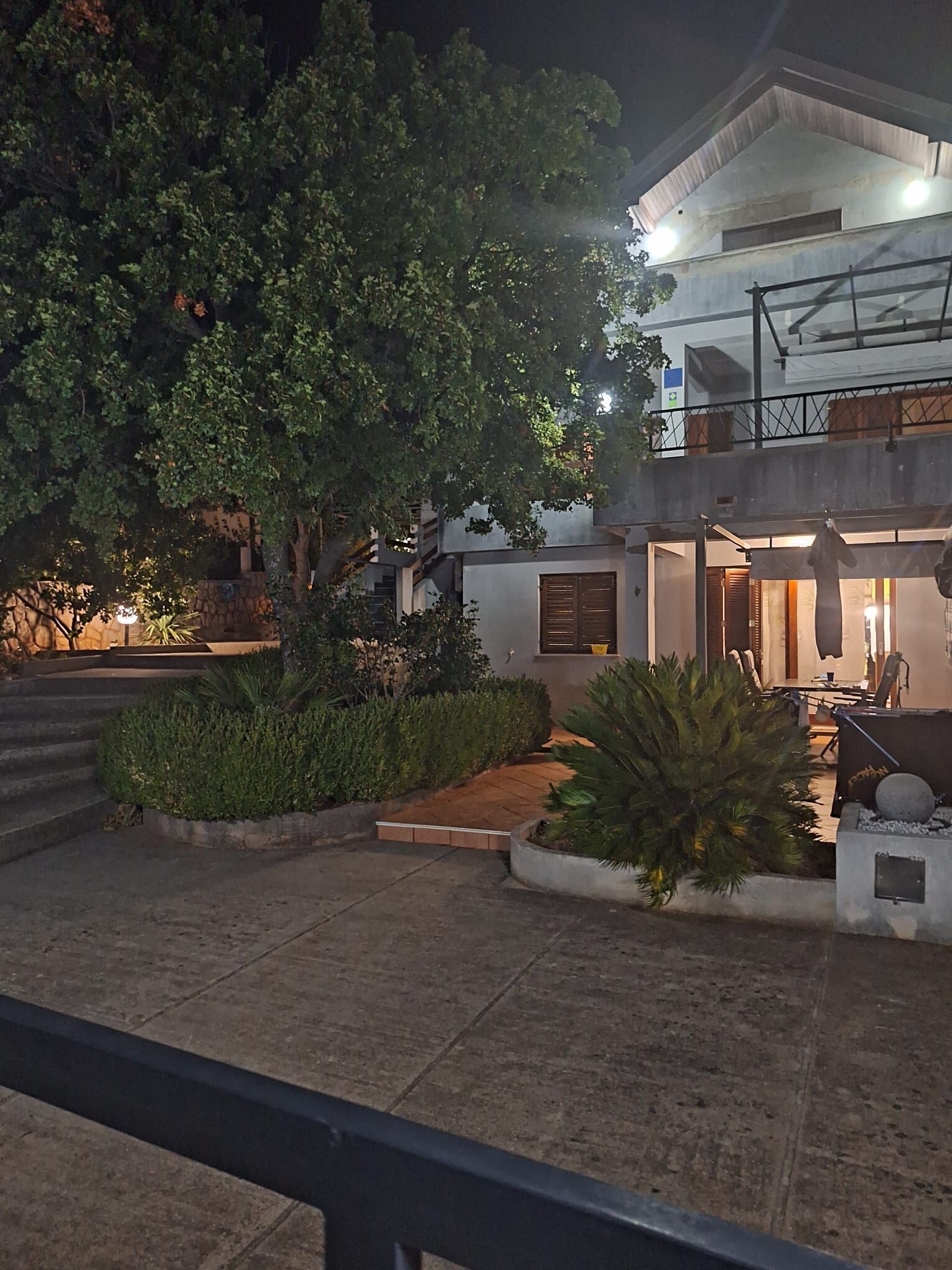 A modern building with a balcony, a staircase, and a well-lit entrance.