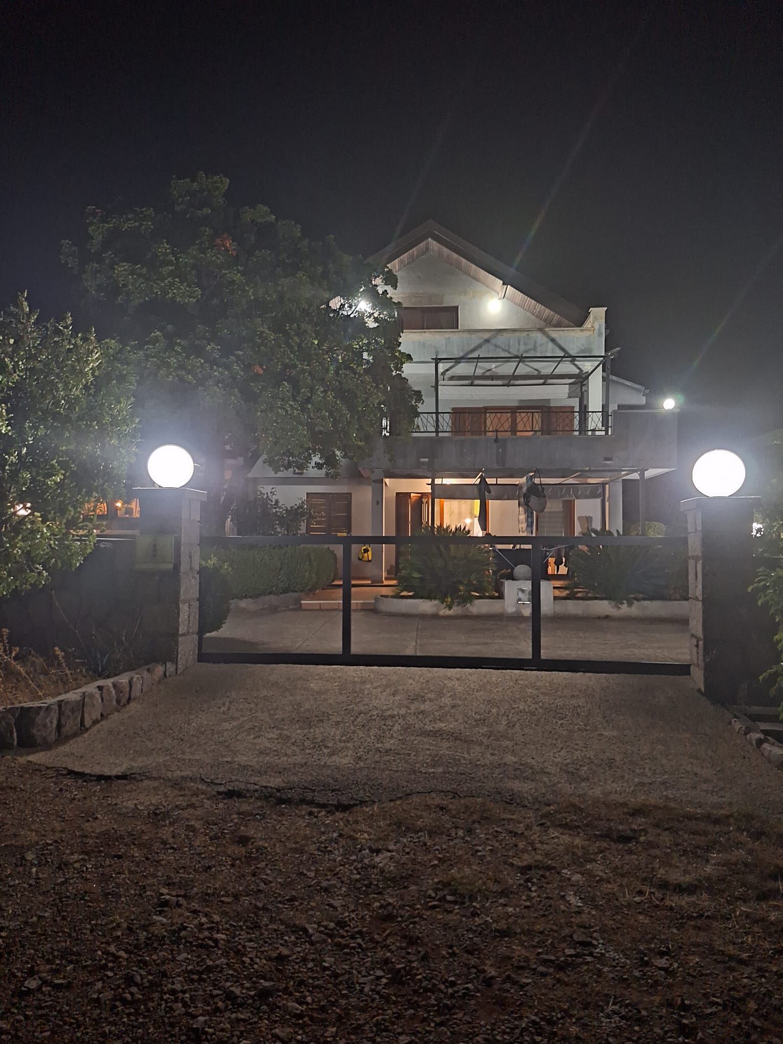 A two-story house with a gated entrance, a driveway, and a well-maintained garden.
