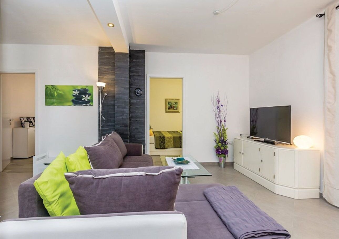 Ein modernes Wohnzimmer mit einer Couch, einem Glastisch, einem Flachbildfernseher und einer weißen Kommode.