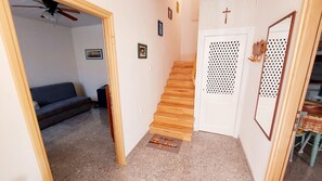 A staircase leading to a door with a cross, a ceiling fan, a couch, and a small rug with cartoon characters. - Apartment Nadi (Mali Losinj)