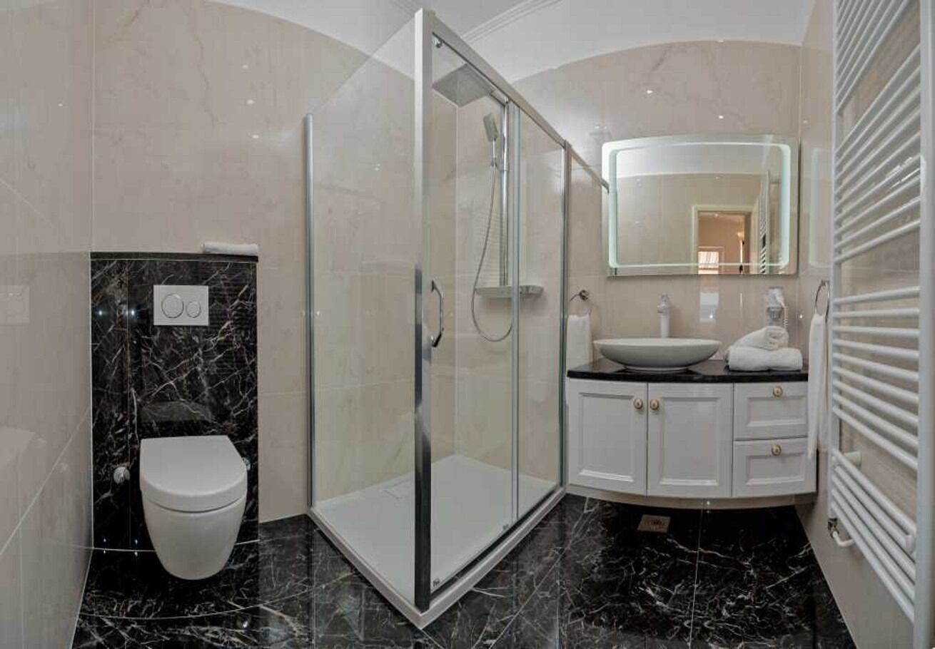 A modern bathroom with a glass-enclosed shower, a white toilet, and a vanity with a mirror.