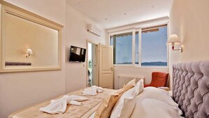 Quarto de hotel com cama, televisão, janela com vista e porta que dá para outro quarto.