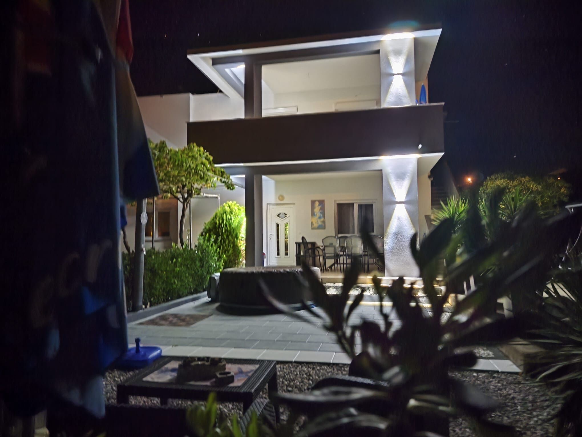 A modern building with a flat roof and a patio area with outdoor furniture.