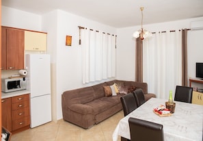 A compact living space with a kitchenette, a sofa, a dining table, and a TV. - Apartment Mira (Rab)