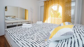 A bedroom with a bed, a mirror, a window with curtains, and a bedside table. - Apartments Zdenka (Rab)