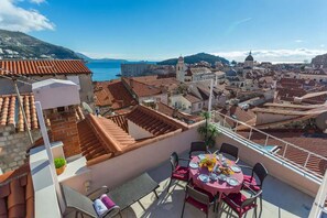 A rooftop terrace with a table set for dining, overlooking a coastal cityscape with terracotta rooftops and historic buildings. - House Star 1 (Dubrovnik)