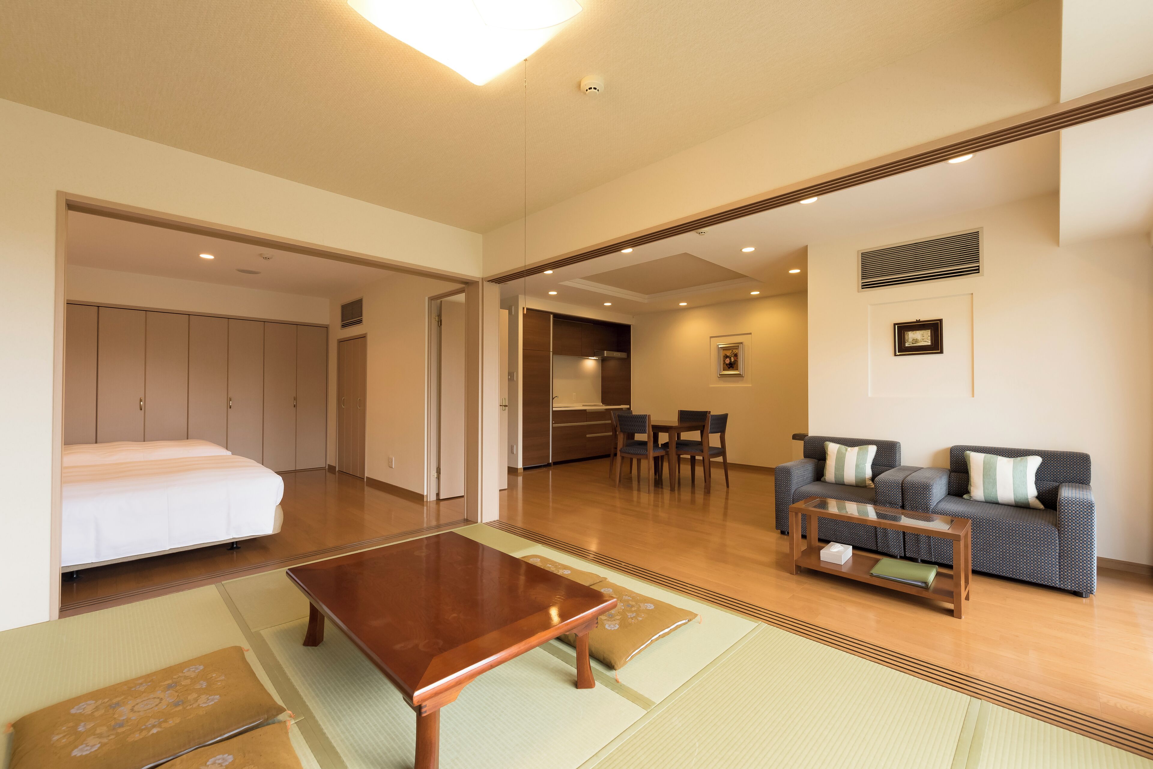 A spacious living area with a sofa set, a coffee table, and a tatami mat.